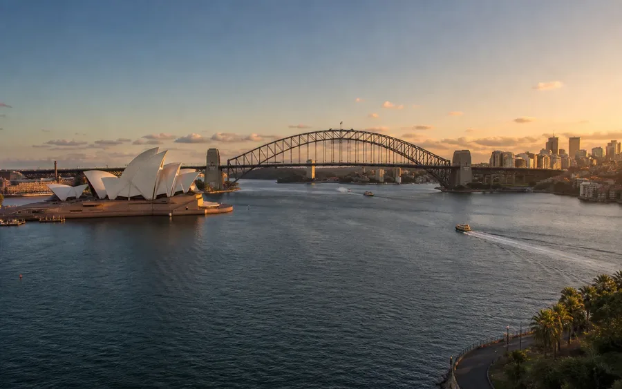 Sydney Opera House and Harbour Bridge across the harbour at golden hour