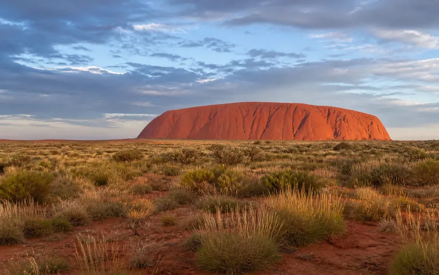 Uluru rising beyond native spinifex in Australia's Red Centre